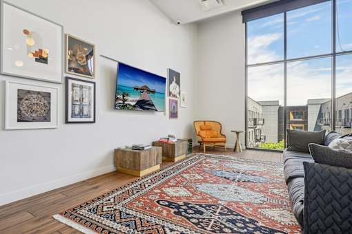 a living room with a couch and a rug and large windows