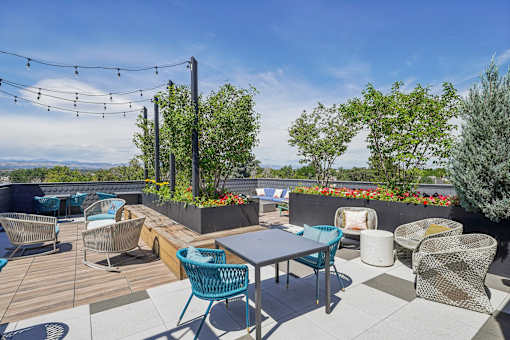 a rooftop patio with tables and chairs and trees