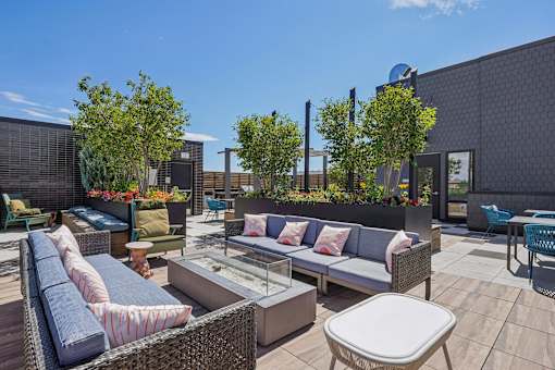 a rooftop patio with couches and tables and trees