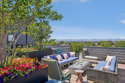 a roof deck with couches and chairs and a view of the city