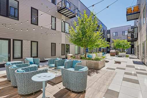a patio with blue chairs and tables and a building in the background