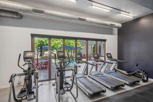 a gym with cardio machines and a patio with a pool