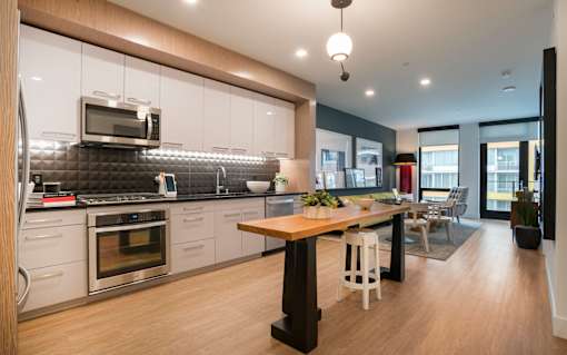 a kitchen and dining room with white cabinets and a wooden table