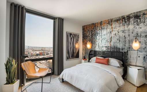 a bedroom with a bed and a window with a city view