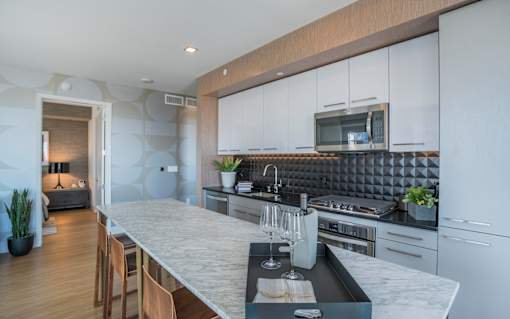 a kitchen with white cabinets and a marble counter top