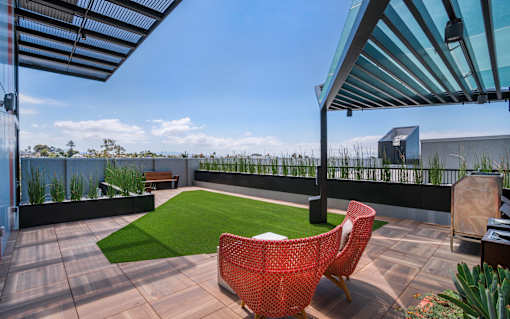 a roof terrace with a lawn and chairs and a pergola