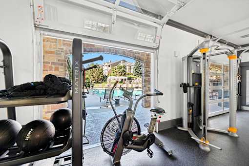 A gym with a rowing machine, a stationary bike, and a bench with weights on it.