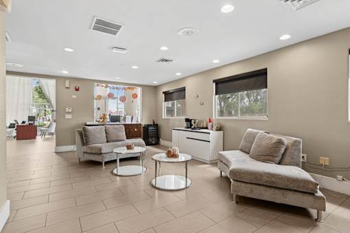 A living room with a grey couch, a white coffee table, and a window with a view of trees.