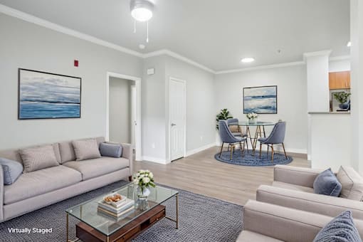 A living room with a grey couch, a glass coffee table, and a painting of a beach scene on the wall.