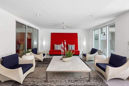 A living room with a red backdrop and white furniture.