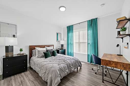A bedroom with a bed, a chair, and a desk.