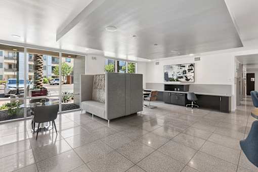 A spacious living room with a grey sofa and a large window overlooking a parking lot.