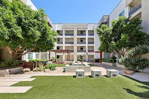 A courtyard with a fountain surrounded by trees and apartment buildings.