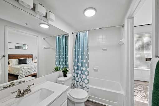 A white bathroom with a toilet, sink, and shower.
