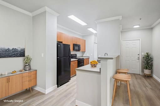 A kitchen with a black fridge, wooden cabinets, and a white island.