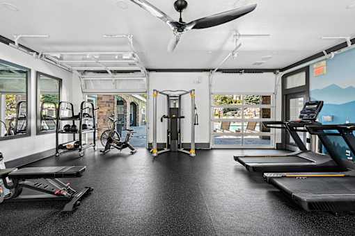 A gym with treadmills, exercise bikes, and a fan.