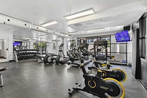 A gym with exercise equipment and a television screen.