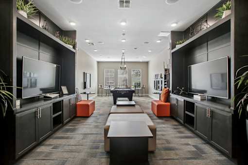 A modern living room with a long table and two TVs.