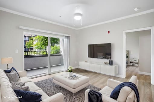 A living room with a white couch, a white coffee table, and a flat screen TV.