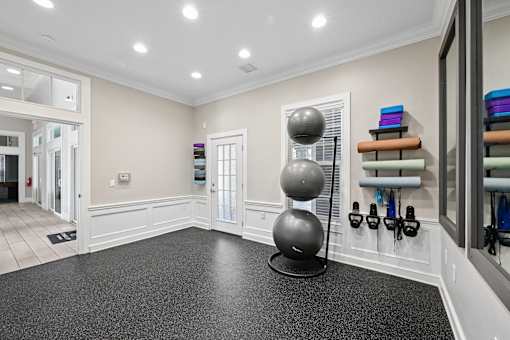 A spacious room with a black exercise ball on a stand.