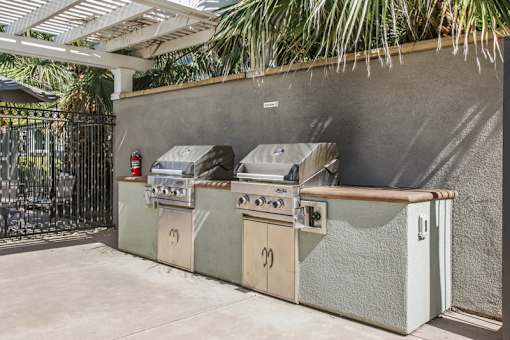 A row of outdoor grills are lined up on a patio.