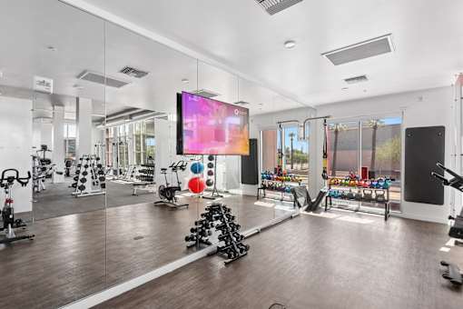 A gym with a variety of equipment including treadmills, weights, and exercise machines.
