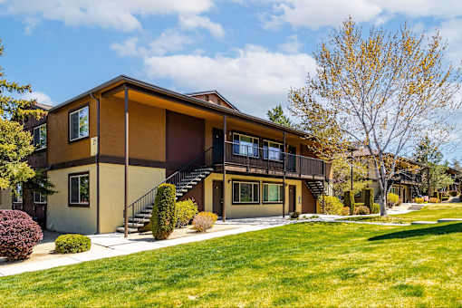 A modern house with a brown and beige exterior and a large front yard.