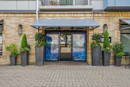 the front of a brick building with doors and potted plants