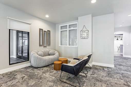 a lounge area with a white couch and chairs and a large window