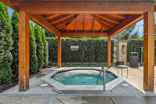 a hot tub is under a wooden pavilion next to a pool