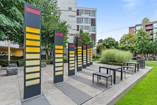 A series of tall, striped poles are lined up in a park.