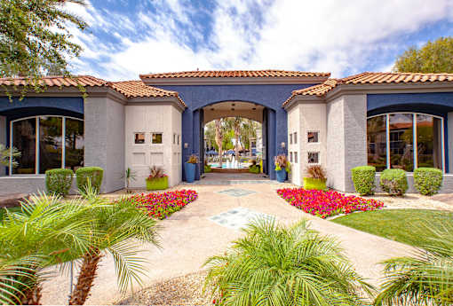 A house with a blue roof and white walls with a garden in front.