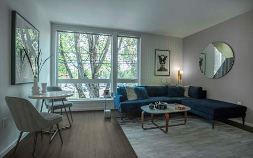 a living room with a blue couch and a table and a large window