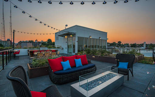 a rooftop patio with furniture and a building in the background