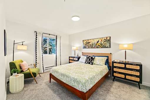 A bedroom with a bed, a chair, and a nightstand.