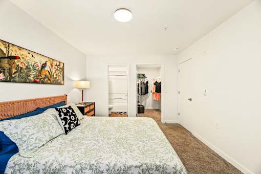 A bedroom with a bed, a lamp, and a painting on the wall.