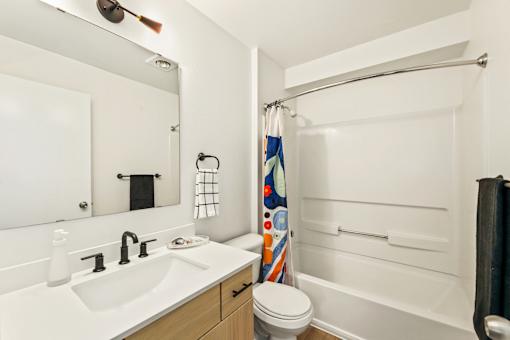 A white bathroom with a toilet, sink, and shower.