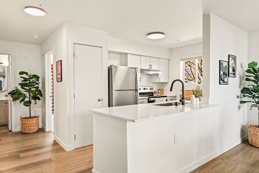 A white kitchen with a refrigerator, sink, and cabinets.