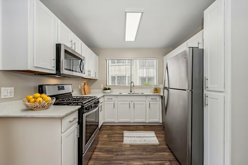 a white kitchen with stainless steel appliances and white cabinets