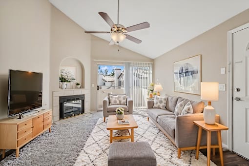 a living room with a ceiling fan and a tv