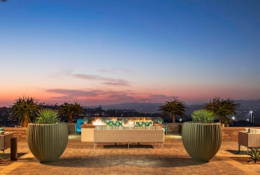 A patio with a couch, chairs, and a table with lights is set up on a rooftop.