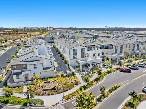 A residential area with houses and a road with cars.