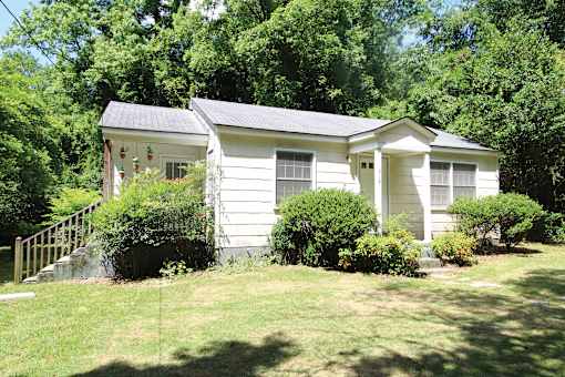 a small white house with a yard and trees