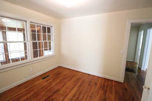 an empty room with a hard wood floor and a window