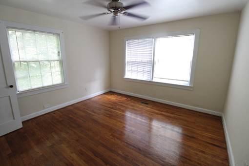 an empty room with a ceiling fan and two windows