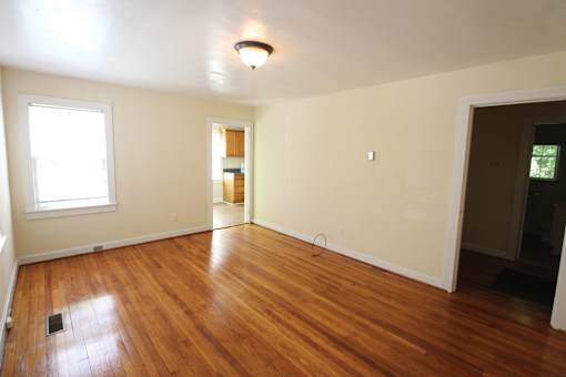 an empty living room with wooden floors and a window