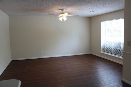 an empty living room with a ceiling fan and a window