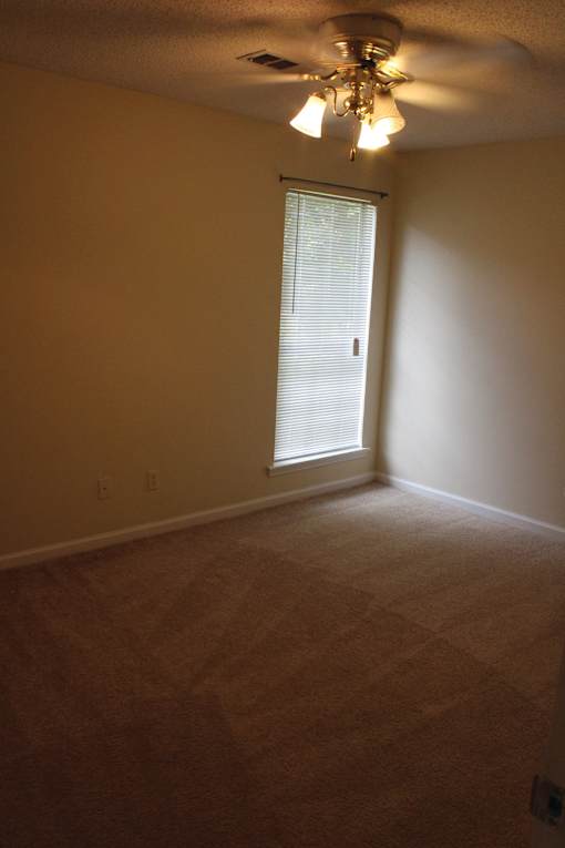 an empty room with a window and a ceiling fan