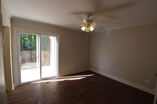 an empty living room with a ceiling fan and a sliding glass door