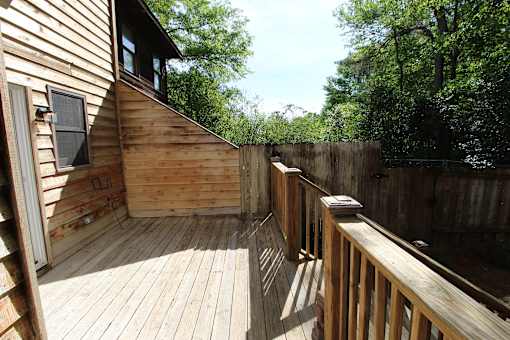 a deck with a wooden fence and a house with trees
